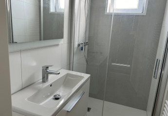 Salle de bain moderne et lumineuse avec lavabo, miroir et douche à Just Nature Light, Marina Strandbad, Pays-Bas.