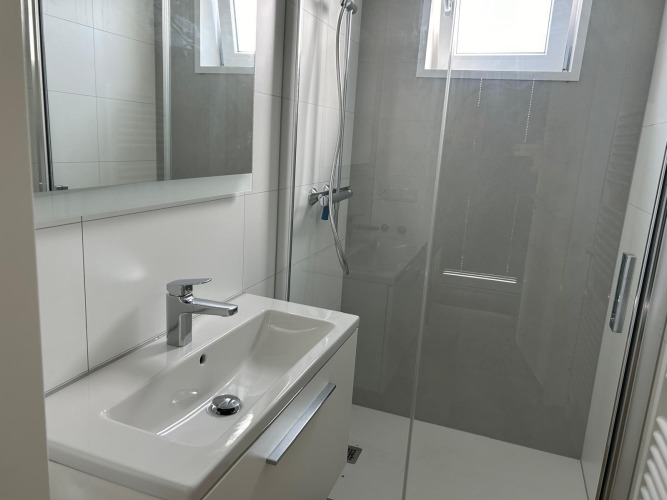 Baño moderno y luminoso con lavabo, espejo y ducha en Just Nature Light en Marina Strandbad, Países Bajos.