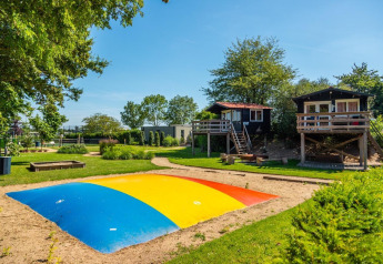 Farverig legeplads med hoppepude og træhytter hos Just Nature Light ved Marina Strandbad, Holland.