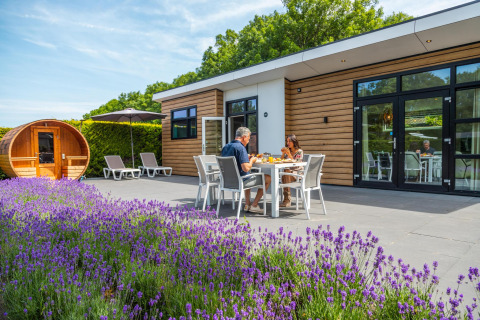 Couple dînant devant une cabane Deluxe Sauna à EuroParcs Noordwijkse Duinen, lavande au premier plan.