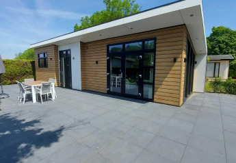 Moderne Deluxe Sauna blokhut met houten gevel en ruim terras bij EuroParcs Noordwijkse Duinen, Nederland.