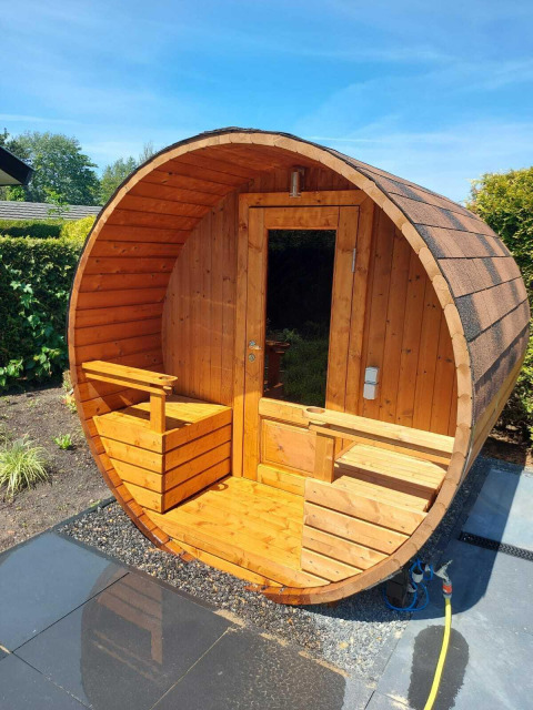 Houten tonvormige sauna buiten bij Deluxe Sauna, EuroParcs Noordwijkse Duinen, Nederland, op een zonnige dag.
