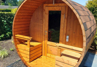 Sauna de barril de madera al aire libre en Deluxe Sauna, EuroParcs Noordwijkse Duinen, Países Bajos, día soleado.