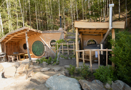 Hobbit House 1, una pequeña casa inspirada en El Señor de los Anillos, con puerta verde y ventanas redondas.