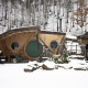 Hobbit House 1 met sneeuw in het bos van Limburg, België, met een ronde groene deur en knusse sfeer.