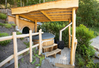 Hobbit House 1 au Cosy Cabins en forêt de Limbourg, Belgique, avec terrasse couverte et bain nordique en bois.