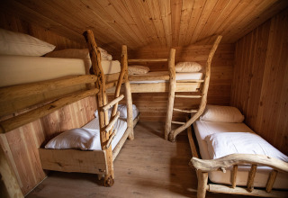 Habitación acogedora en Hobbit House 1 con cuatro literas de madera rústica en Cosy Cabins, bosque de Limburg, Bélgica.