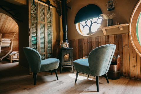 Deux fauteuils devant un poêle dans Hobbit House 1 chez Cosy Cabins, forêt de Limburg, Belgique.