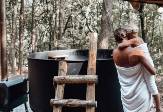 Moeder en kind gewikkeld in handdoeken bij een buiten hot tub aan Hobbit House, Cosy Cabins, Limburg.