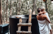 Mother and child in towels by an outdoor hot tub at Hobbit House, Cosy Cabins in the forest of Limburg, Belgium.