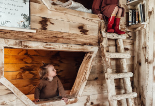 Dos niños juegan en una habitación de literas de madera en Hobbit House en Cosy Cabins, bosque de Limburg, Bélgica.