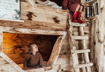 To børn leger i et hyggeligt træværelse med køjesenge i Hobbit House ved Cosy Cabins, Limburg, Belgien.
