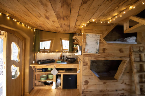 Acogedor interior de madera de Hobbit House en Cosy Cabins, bosque de Limburg, Bélgica, con luces suaves.