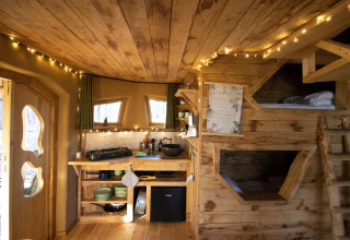 Knus houten interieur van Hobbit House bij Cosy Cabins in het Limburgse bos, België, met sfeerverlichting.