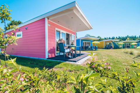 Tiny house colorate al Holiday park Ackersate, Olanda, prati verdi e cielo sereno e azzurro.