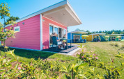 Pequeñas casas de colores en Holiday park Ackersate, en Países Bajos, césped y cielo soleado.