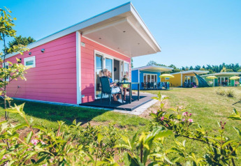 Pequeñas casas de colores en Holiday park Ackersate, en Países Bajos, césped y cielo soleado.