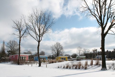 Bunte Tiny Houses im verschneiten Holiday Park Ackersate, Valley Chalet, Niederlande, Wintertag.