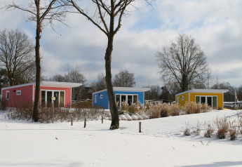 Pequeñas casas coloridas en Valley Chalet con nieve en Holiday park Ackersate, Países Bajos, en invierno.