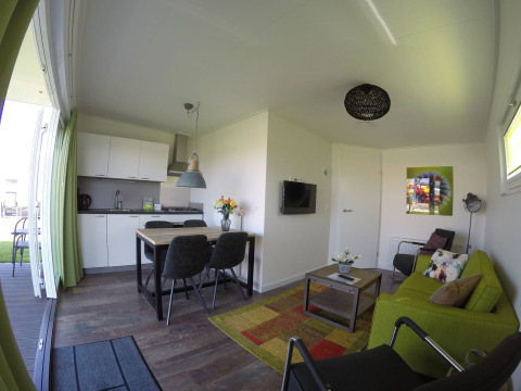 Sala de estar y cocina modernas dentro de Valley Chalet, una tiny house en Holiday park Ackersate, Países Bajos.