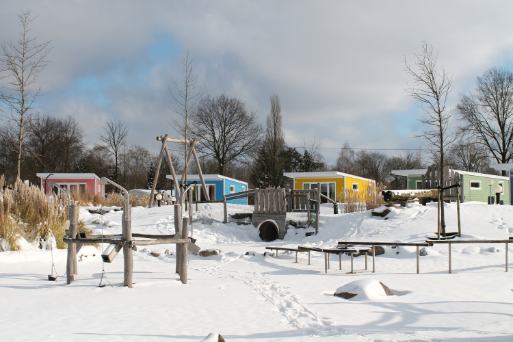 Bunte Tiny Houses und verschneiter Spielplatz im Valley Chalet, Holiday park Ackersate, Niederlande.