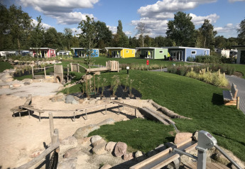 Kleurrijke tiny houses bij Valley Chalet, Holiday park Ackersate in Nederland, met speeltuin en grasveld.