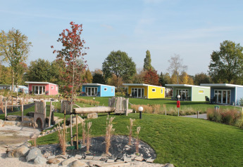 Kleurige tiny houses bij Valley Chalet, Holiday park Ackersate, Nederland, omgeven door groen grasveld.