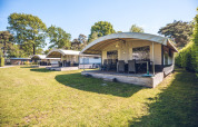 Safaritentvilla’s op vakantiepark Ackersate in Nederland met houten veranda’s en groene omgeving.