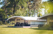 Safari tent villa at Holiday park Ackersate in the Netherlands, surrounded by trees and grassy area.