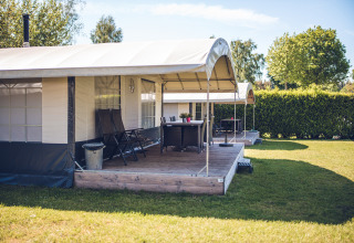 Safaritentvilla in vakantiepark Ackersate in Nederland, met houten terras, stoelen en groene tuin.