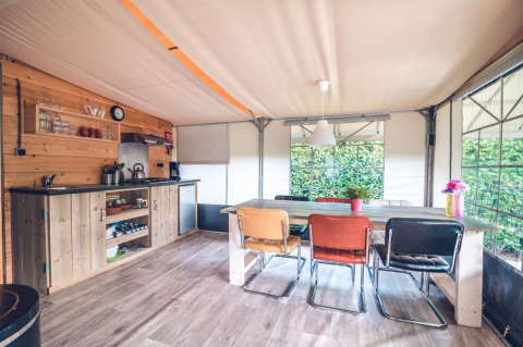 Vista interna di una cucina e zona pranzo in tenda safari al Holiday park Ackersate, Paesi Bassi.
