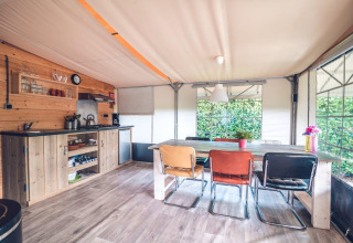 Vista interna di una cucina e zona pranzo in tenda safari al Holiday park Ackersate, Paesi Bassi.