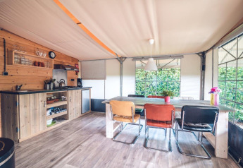 Vue intérieure d'une tente safari avec cuisine et salle à manger au Holiday park Ackersate, Pays-Bas.