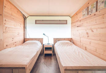 Binnenaanzicht van Tentvilla safaritent bij Vakantiepark Ackersate, met twee eenpersoonsbedden en houten wanden.