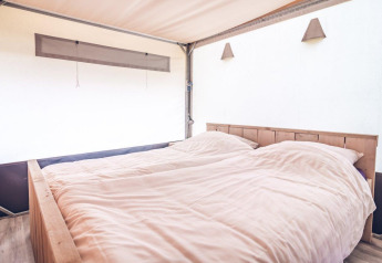 Helles Schlafzimmer im Safarizelt der Ferienpark Ackersate, Niederlande, mit großem Doppelbett.