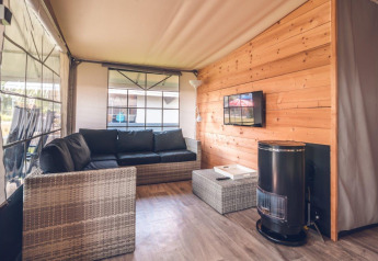 Gemütliches Wohnzimmer im Safarizelt der Holiday park Ackersate, mit Sofa, TV und Holzverkleidung.