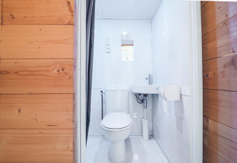 Baño de camping moderno con inodoro y lavabo en una tienda safari en Holiday park Ackersate, Países Bajos.