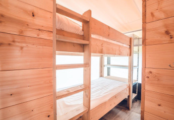 Wooden bunk bed in a bright interior of a Tentvilla safari tent at Holiday park Ackersate, Netherlands.
