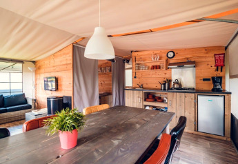 Interior view of a luxury safari tent villa with wooden décor at Holiday park Ackersate in the Netherlands.