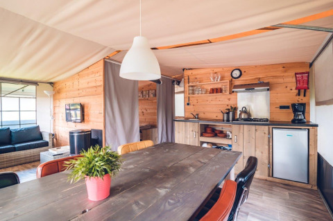 Interior view of a luxury safari tent villa with wooden décor at Holiday park Ackersate in the Netherlands.