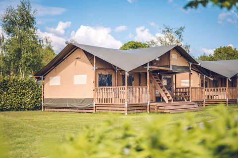 Safari tent 'Red Deer' at Holiday park Ackersate in the Netherlands, with wooden porch and green summer lawn.
