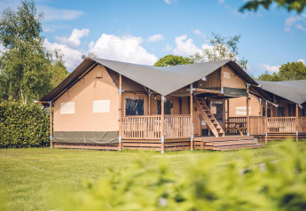 Safari tent 'Red Deer' at Holiday park Ackersate in the Netherlands, with wooden porch and green summer lawn.