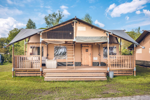 Safaritent 'Red Deer' op vakantiepark Ackersate in Nederland, met ruime veranda en houten trap.