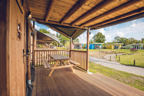 Blick von der Holzveranda des Safari-Zelts 'Red Deer' im Ferienpark Ackersate, Niederlande, auf bunte Häuser.
