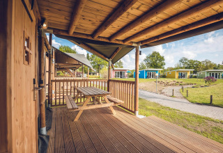Vista dal portico in legno della tenda Safari 'Red Deer' a Holiday park Ackersate, Paesi Bassi, con bungalow.