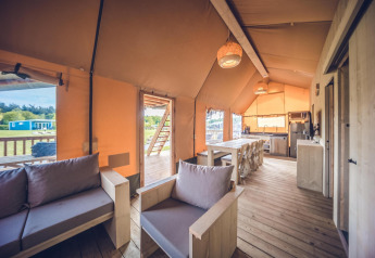 Interieur van safaritent 'Red Deer' op Vakantiepark Ackersate in Nederland met houten meubels en vloer.