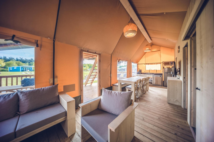Interieur van safaritent 'Red Deer' op Vakantiepark Ackersate in Nederland met houten meubels en vloer.