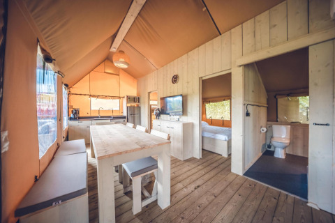 Binnenzicht van safaritent 'Red Deer' op vakantiepark Ackersate in Nederland met eetruimte en keuken.