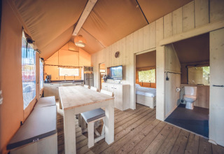 Interieur van safaritent 'Red Deer' op Vakantiepark Ackersate in Nederland met eettafel en keuken.