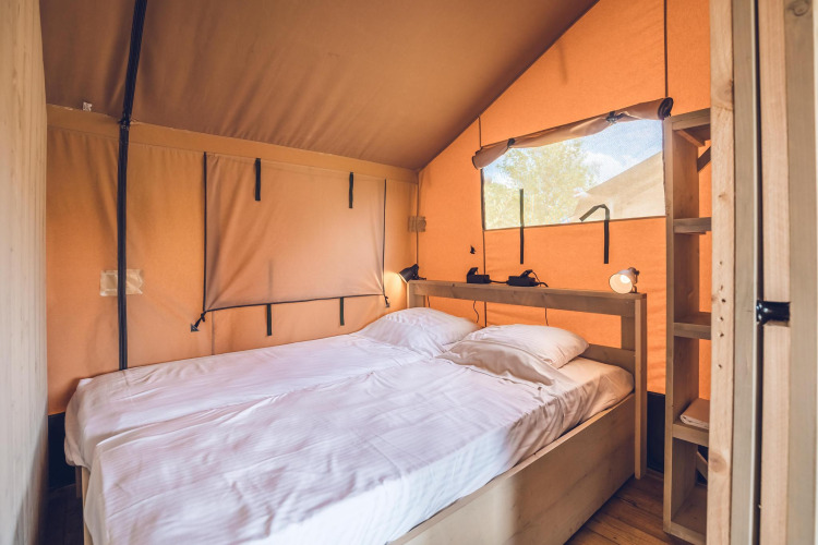 Interieur van safaritent 'Red Deer' op Vakantiepark Ackersate met comfortabel tweepersoonsbed en houten details.